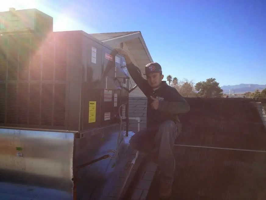 HVAC technician performing Air Duct Repair on a rooftop unit in Sanger